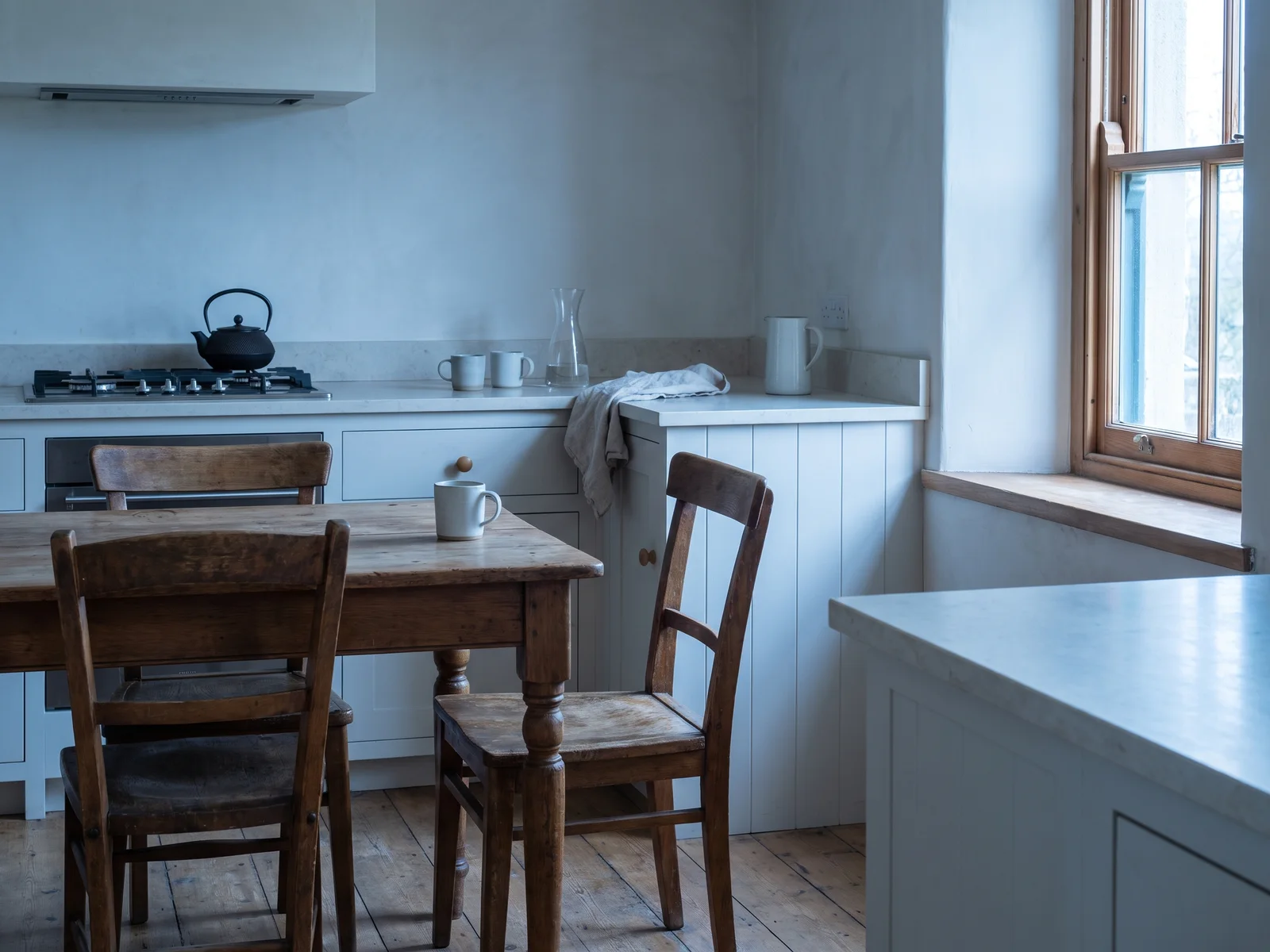 The kitchen as it was photographed for the inventory: a wooden table and chairs, a range, and a window on the right.